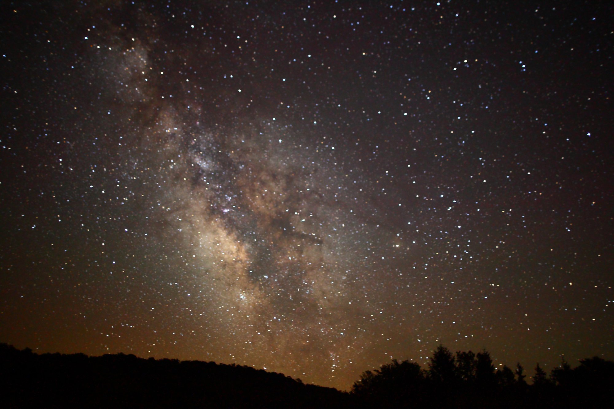 The bright core of the Milky Way over a dark Appalachian treeline